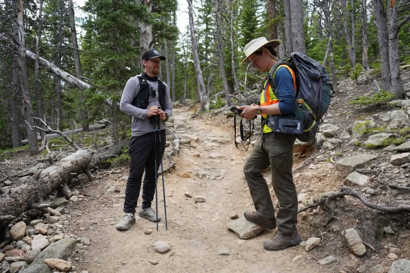 Researchers gathering field data along a forest trail