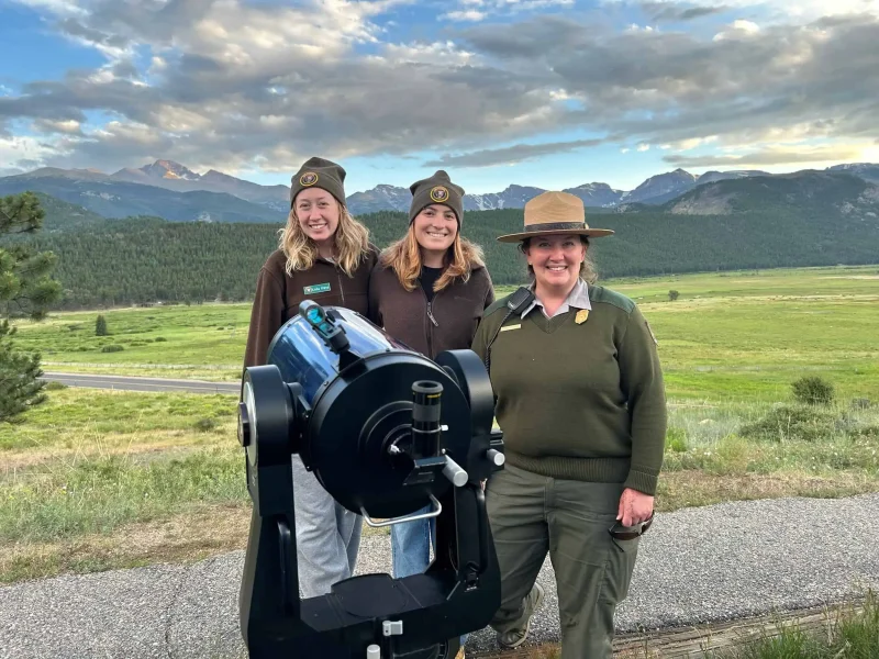 Two night sky interns and a park ranger standing beside a telescope