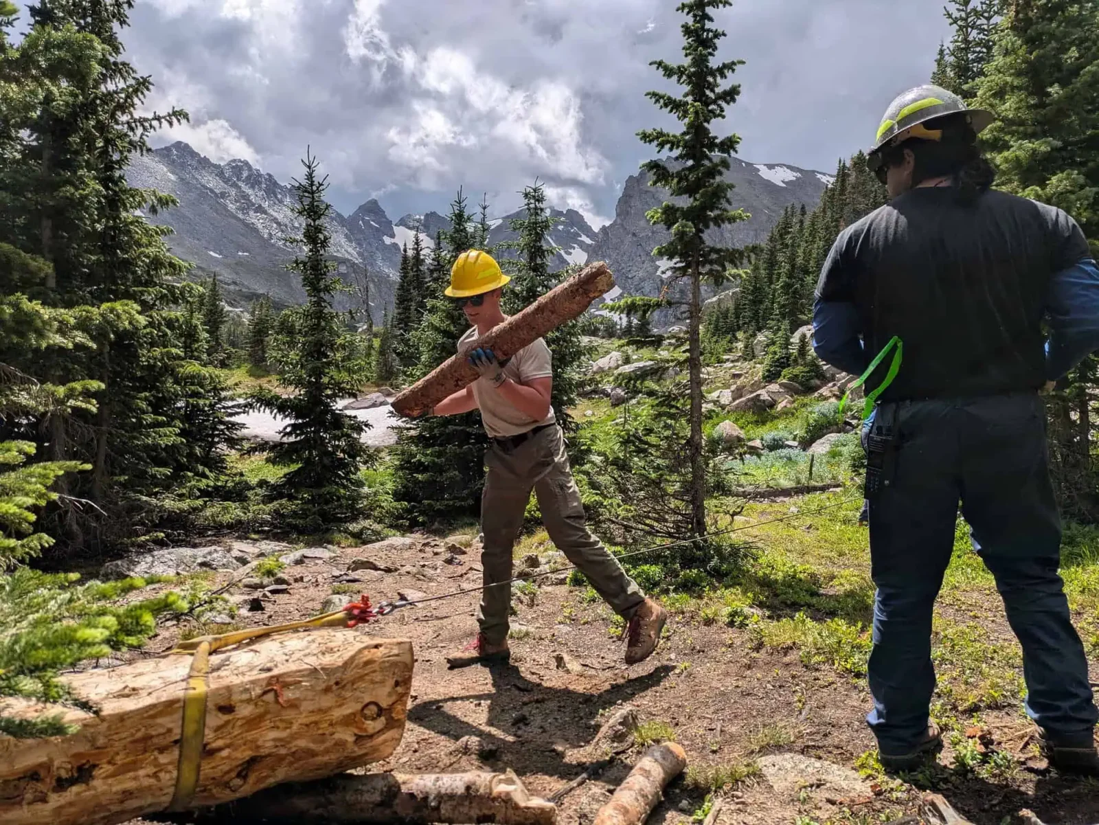 Conservation Corps crew member carrying a log for trail construction